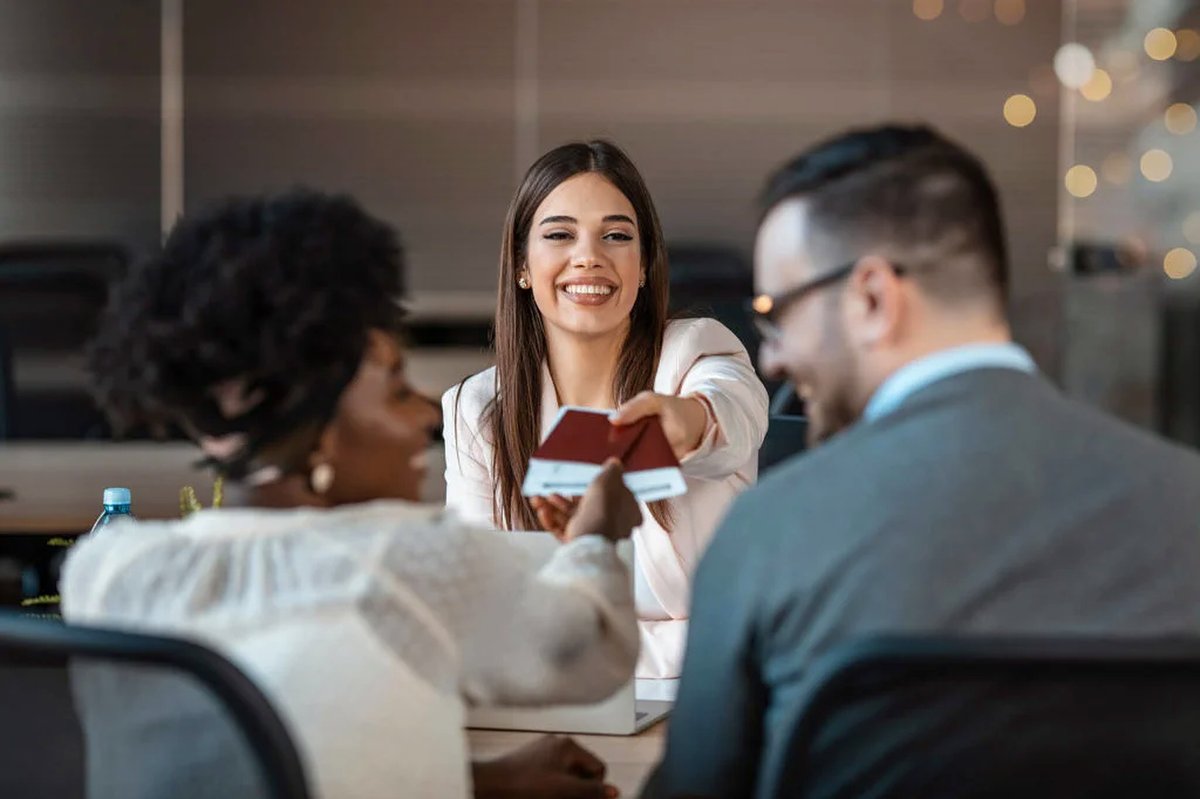 Lächelnder Reiseberater übergibt am Schalter die Pässe an ein glückliches Paar — Blog‑Moment «Letzte Gedanken» vor der Abreise.