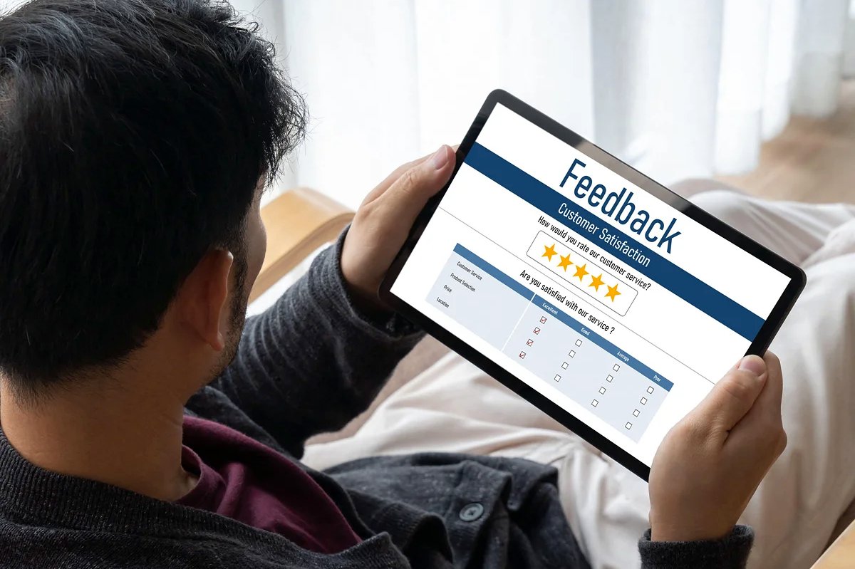 Blick über die Schulter einer Person mit Tablet, das eine Kundenumfrage mit 5‑Sterne‑Bewertung anzeigt — Blogbild: „Bewertungen erzählen Geschichten, die Werbung nie erzählen wird“