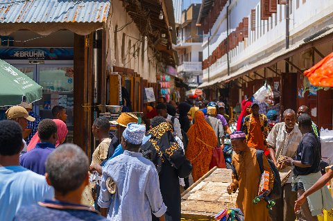 Busy Stone Town market street in Zanzibar City with wooden shutters, stalls and a bustling crowd