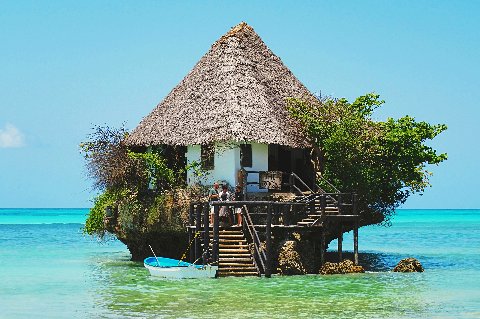 Palm-fringed Zanzibar beach with thatched umbrellas and sun loungers on pristine white sand