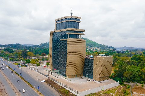 Modern gold-and-glass office tower with surrounding greenery and rolling hills in Tanzania