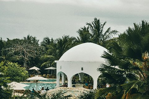 White domed pavilion and swim-up bar amid palm trees beside a lagoon-style pool at a coastal Kenyan resort